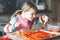 Adorable little toddler girl making italian pizza at home. Cute happy child having fun in home kitchen, indoors. Kid