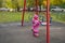 Adorable little toddler swinging on a swing in the playground