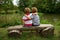 Adorable Little Twin Brothers Sitting on a Wooden Bench, Embracing Each Other and Looking at Beautiful Lake