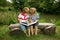 Adorable Little Twin Brothers Sitting on a Wooden Bench and Reading a Book Very Carefully Near the Beautiful Lake