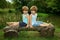 Adorable Little Twin Brothers Sitting on a Wooden Bench, Smiling and Looking at Each Other Near the Beautiful Lake