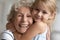 Adorable loving small child girl embracing happy older grandmother, portrait.