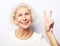 Adorable mature wrinkled woman smiles broadly and gives peace sign, enjoys cool nice day