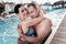 Adorable millennial couple hugging and smiling in swimming pool