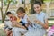 Adorable multicultural friends sitting on bench in schoolyard and reading books