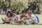 Adorable multicultural schoolkids sitting on lawn and reading books