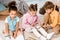 adorable multiethnic children sitting on carpet and
