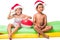 adorable multiethnic kids in santa hats sitting on swimming mattresses