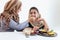 Adorable Muslim happy girl sits at kitchen table, kid with hijab enjoy eating traditional Islamic halal food with mother hand on