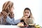 Adorable Muslim happy girl sits at kitchen table, kid with hijab enjoy eating traditional Islamic halal food with mother hand on