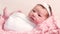 Adorable newborn lies in pink wicker bed