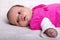 Adorable one month old baby girl in pink dress lies on a soft blanket