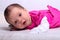 Adorable one month old baby girl in pink dress lies on a soft blanket