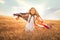 Adorable patriotic girl in white dress wearing an American flag while running in a beautiful wheat field