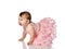 Adorable positive little baby girl in stylish pink sprincess dress creeping on floor, smiling and looking ahead