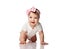 Adorable positive little baby girl in white body, hair bow decoration and barefoot creeping on floor, smiling and looking aside