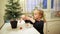 Adorable preschooler girl decorating little Christmas tree with miniature toys at home