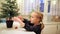 Adorable preschooler girl decorating little Christmas tree with miniature toys at home