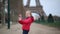 Adorable preschooler girl with a doll in front of the Eiffel tower in Paris, France