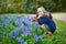 Adorable preschooler girl enjoying nice spring day in park during hyacinth blooming season