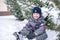 Adorable preschooler in winter wear sit amoung snow and play wit