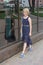 Adorable preteen blonde kid girl in fashionable dress walking down the street, she smiles and is confident