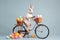 adorable rabbit riding a bicycle with a basket full of easter eggs on blue background. AI generative