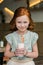 adorable red haired girl drinking milkshake with straw and smiling
