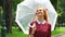 Adorable red haired girl walking with umbrella in sunny park