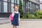 adorable red haired schoolgirl in spectacles holding backpack and smiling