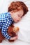 Adorable redhead toddler baby sleeping with plush toy in flannel