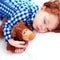Adorable redhead toddler baby sleeping with plush toy in flannel pajamas