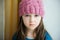 Adorable sad child girl in pink knitted hat