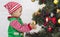 Adorable Santa helper decorating Christmas tree at home