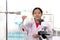Adorable schoolgirl in lab coat doing science experiments, young scientist showing at blue test tube and learning science