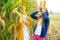 Adorable sisters playing in a corn field on beautiful autumn day. Pretty children holding cobs of corn. Harvesting with kids.