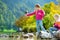 Adorable sisters playing by Konigssee lake in Germany on warm summer day. Cute children having fun feeding ducks and throwing ston