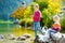 Adorable sisters playing by Konigssee lake in Germany on warm summer day. Cute children having fun feeding ducks and throwing ston