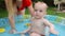 Adorable smiling baby playing in inflatable swimming pool at backyard