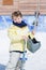 Adorable smiling boy holding helmet and skis