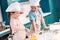 adorable smiling children in chef hats and aprons making dough together