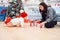 Adorable smiling infant crawling on the parquet to the christmas gifts near his mom which sits on the floor.
