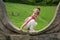 Adorable Smiling Little Girl Crouching On The Stonewall And Looking At The Camera In The Park