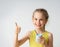 Adorable smiling little girl with a delicious dessert in hand looking at camera showing thumb up. Close up studio