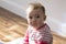 Adorable solemn looking fair baby girl sitting on floor staring ahead