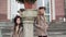 Adorable stylish girls standing near column and smiling at camera