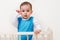 Adorable suprised baby toddler posing in the bed with hand on face on white background