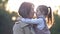 An adorable, sweet little girl hugs her young mother during a walk in a spring park.