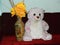An adorable teddy bear sat on the Sofa with a Flower Vase