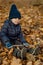 Adorable three year old caucasian boy sitting on the ground covered with yellow fallen maple leaves